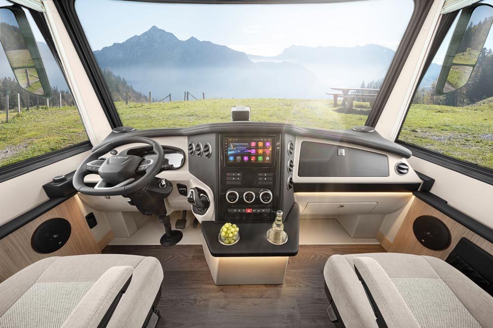 Modern Cockpit eines Wohnmobils mit hellem Holz, großem Display und Bergblick