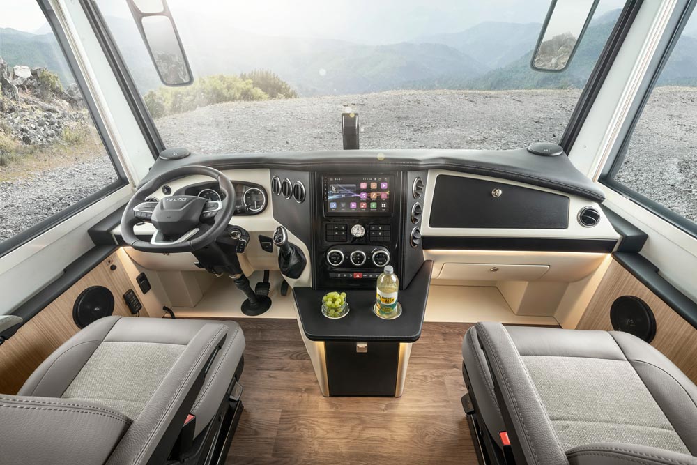 Modernes Wohnmobil Cockpit mit zwei grauen Sitzen, Flaschen und Trauben auf Konsole