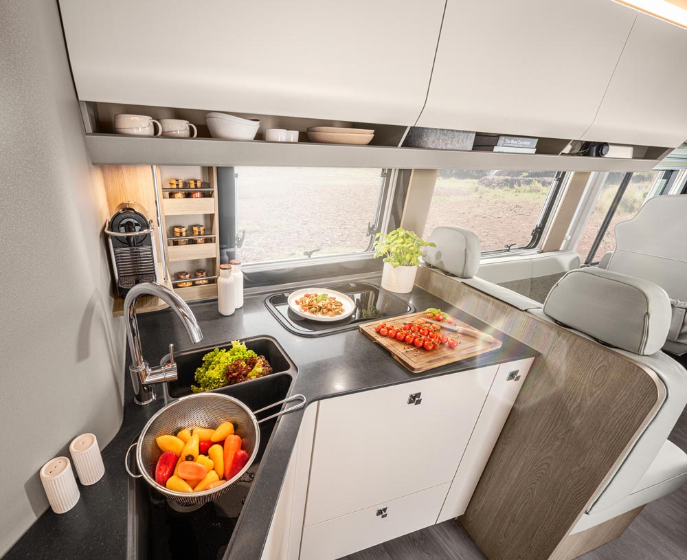 Eine modern eingerichtete Wohnmobilküche mit frischem Gemüse und elegantem Licht