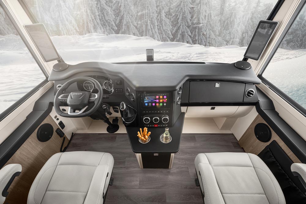 Modern Cockpit eines Wohnmobils mit weißem Leder, Holzdekor und Bergen im Hintergrund