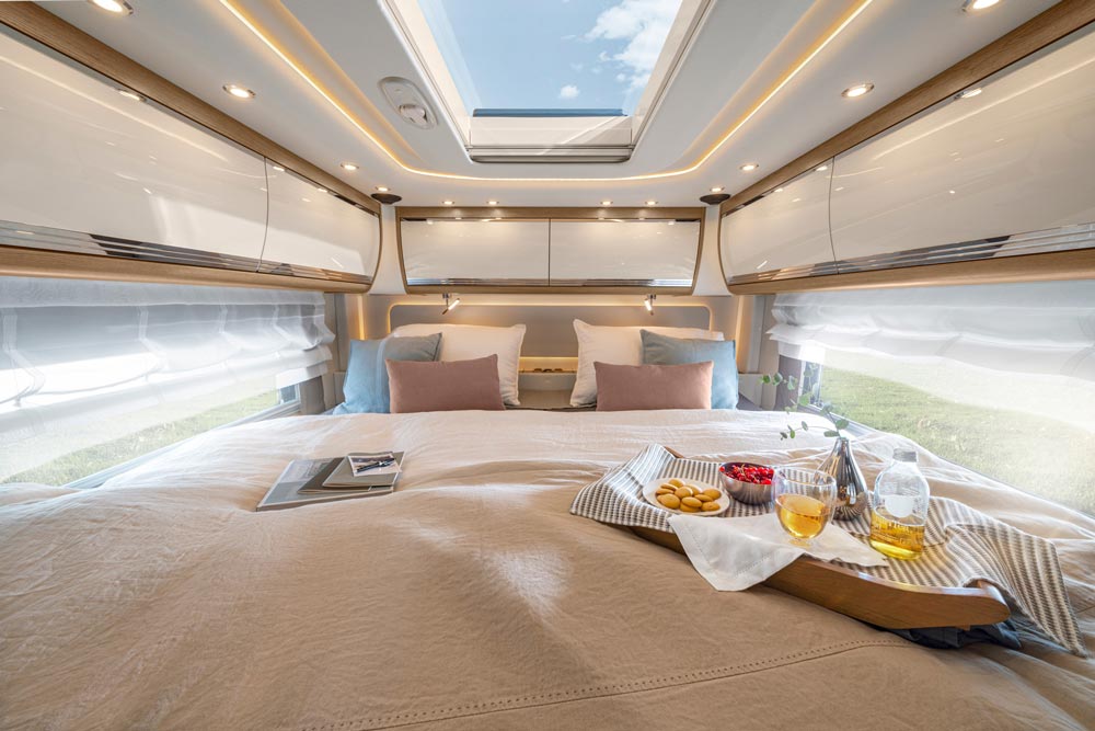 Ein helles Schlafzimmer im Wohnmobil mit großem Bett und Frühstückstablett