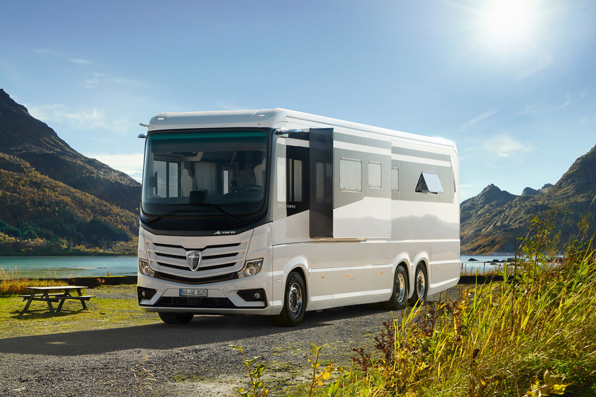 Ein luxuriöses weißes Wohnmobil steht auf einem Parkplatz vor malerischer Bergkulisse