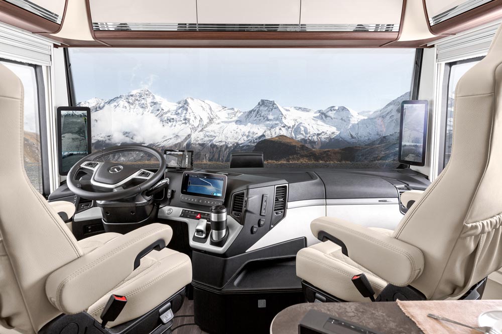 Zwei helle Ledersitze im luxuriösen Cockpit eines Wohnmobils mit Bergblick