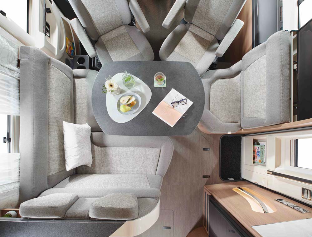 Helle wohnliche Wohnmobil Sitzgruppe mit grauen Polstern und gedecktem Tisch