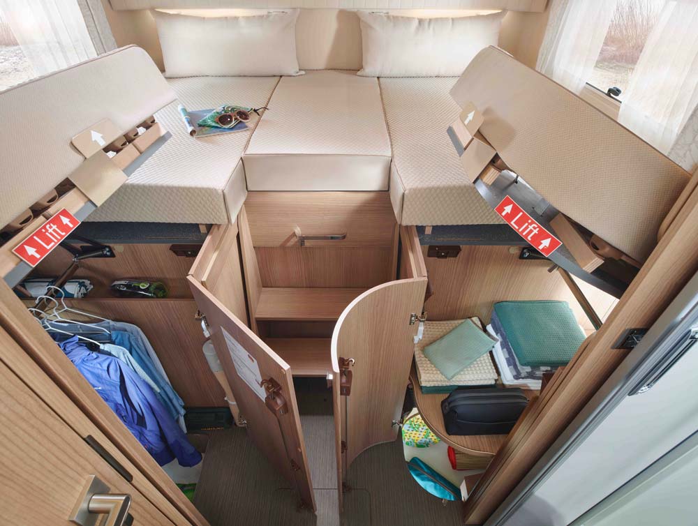Ein aufgeräumter Wohnmobilbereich mit offenem Staufach, Kleidung und Utensilien