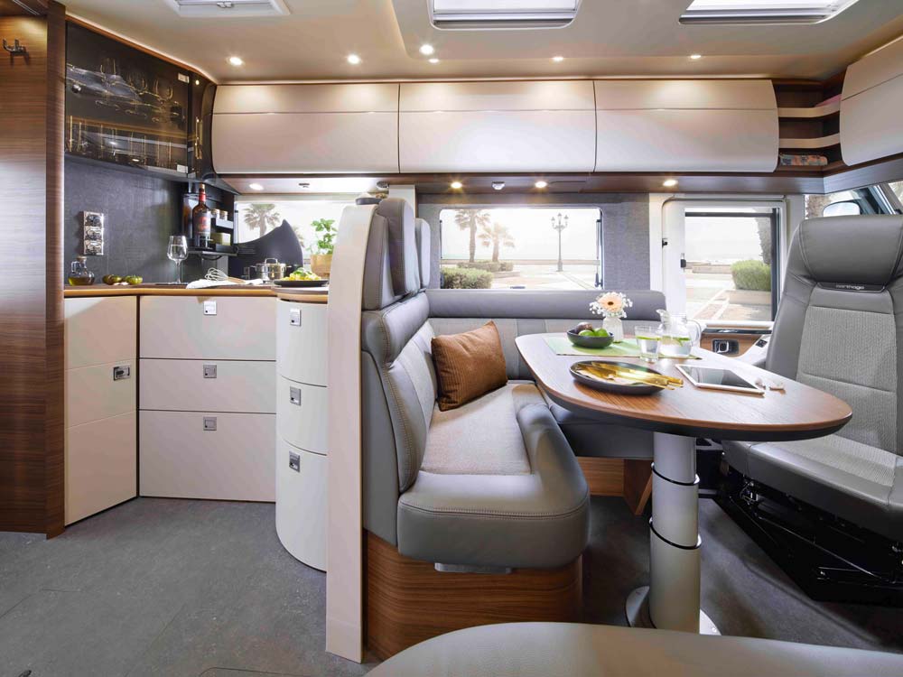 Modern Wohnmobil Innenraum mit hellen Möbeln, grauen Polstern und gedecktem Tisch