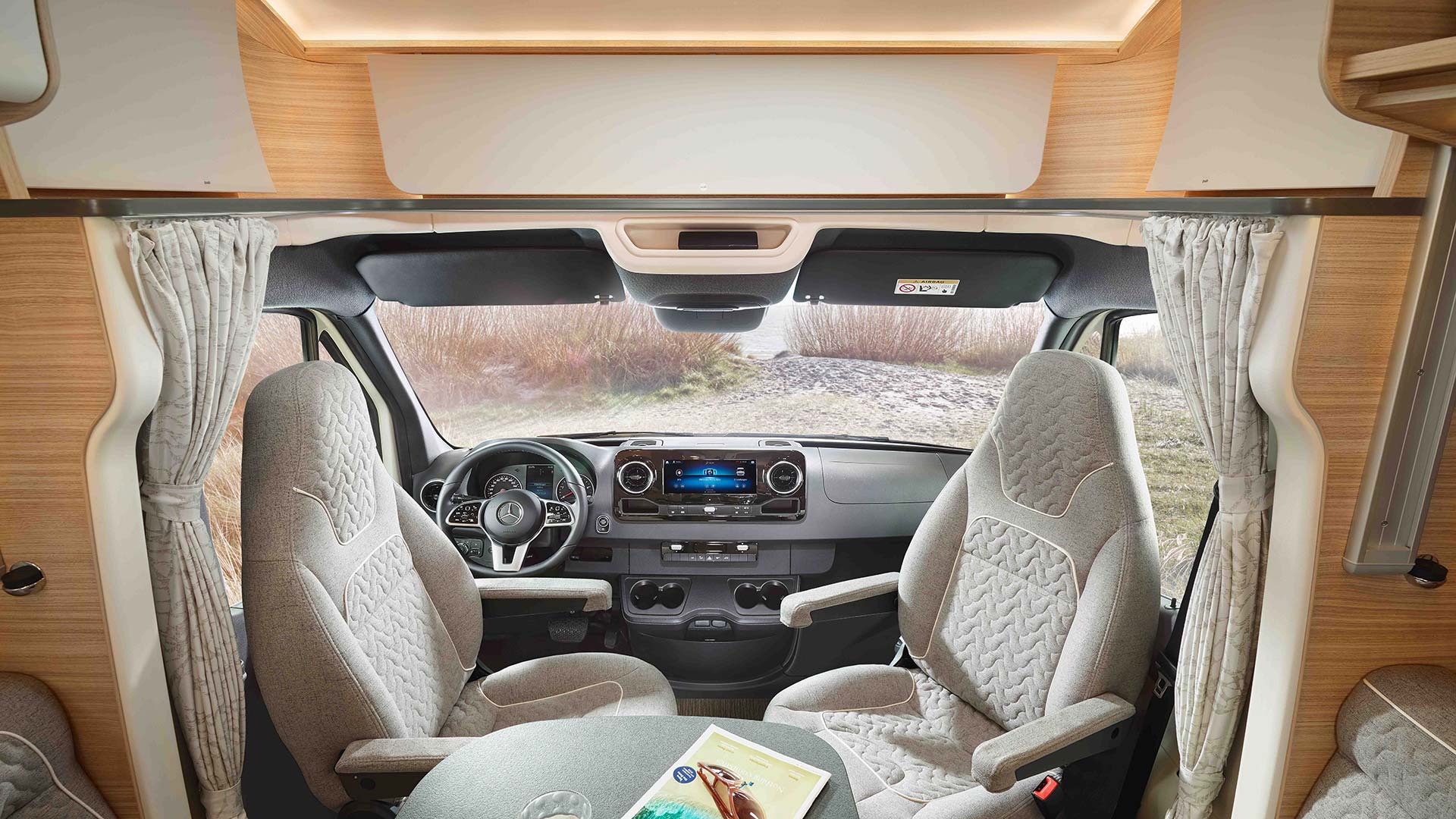 Zwei bequeme beige Sitze in einem modernen Wohnmobil mit Blick auf einen See