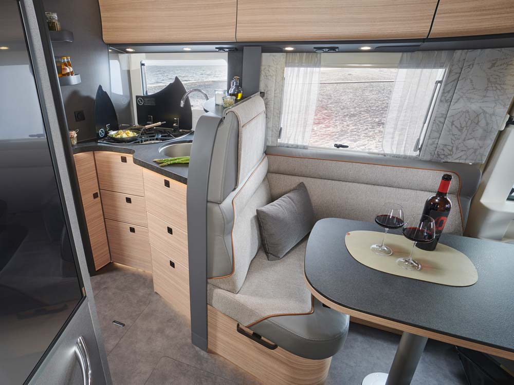 Eine moderne Wohnmobilküche mit hellen Holzmöbeln und gedecktem Tisch für zwei