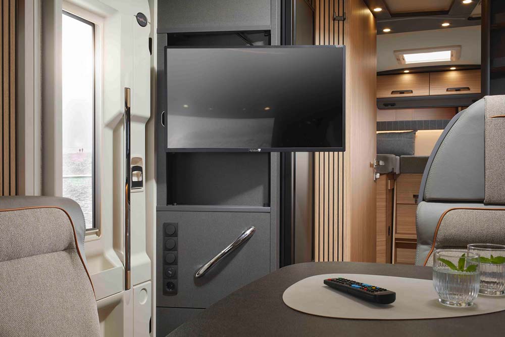 Modern Wohnmobil Innenraum mit grauen Polstern, Fernseher und Fernbedienung auf Tisch