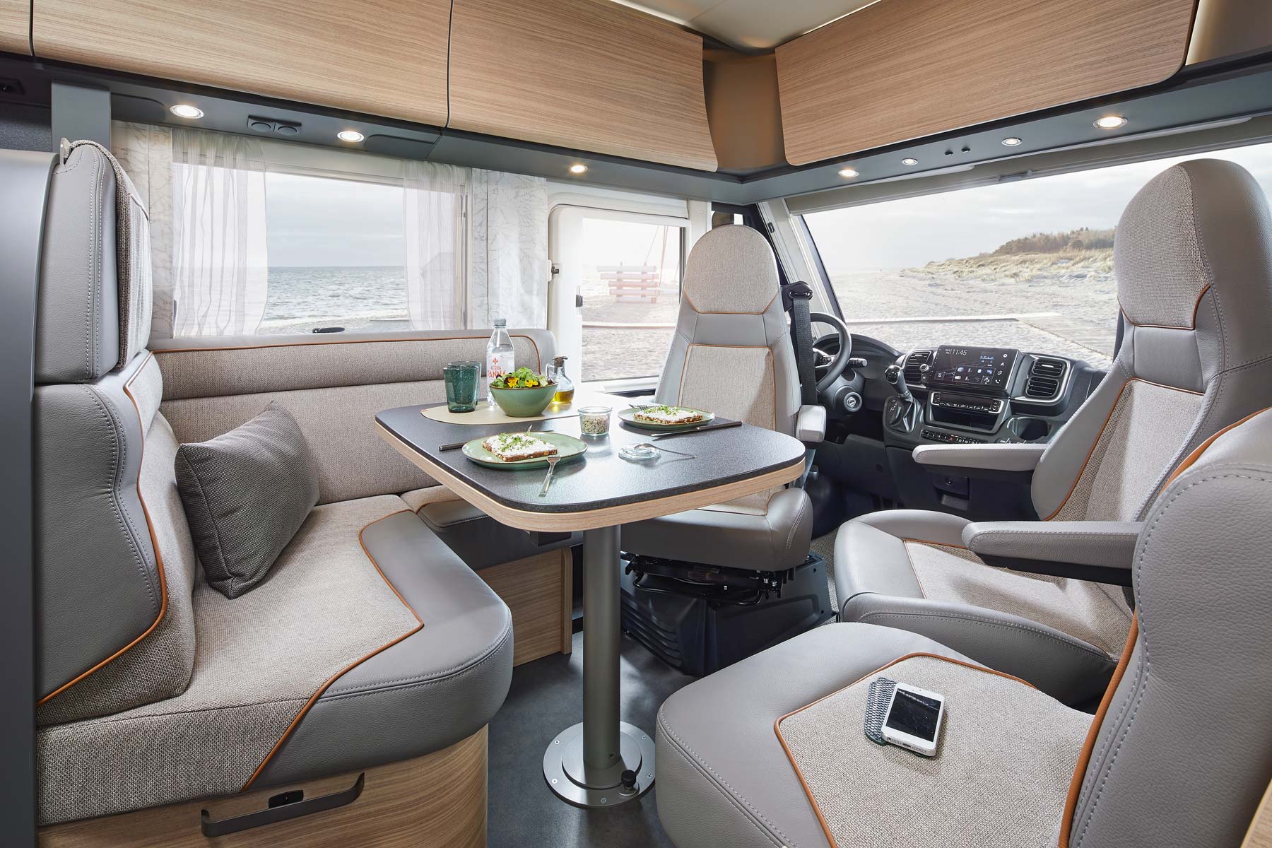 Innenansicht eines modernen Campervans am Strand mit gedecktem Tisch und hellem Interieur