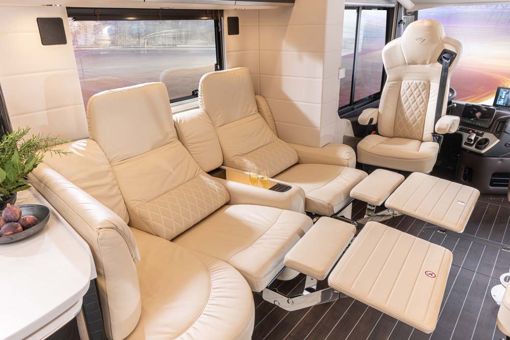 Drei bequeme cremefarbene Ledersessel mit Fußstützen stehen in einem luxuriösen Wohnmobil