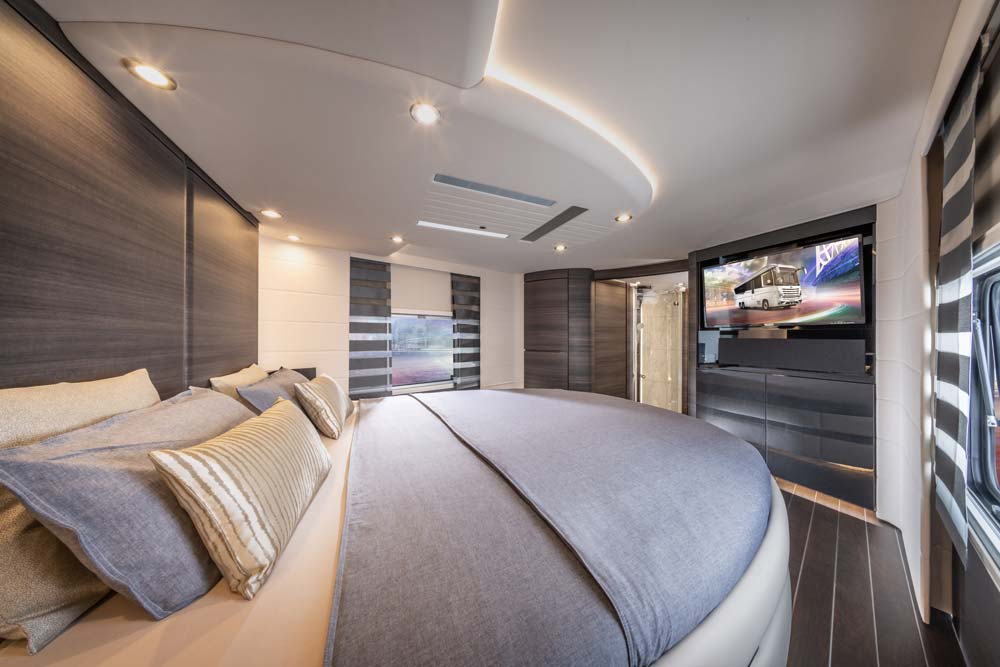 Modern Schlafzimmer mit großen runden Bett, blauen Bezügen und stilvollem Lichtdesign