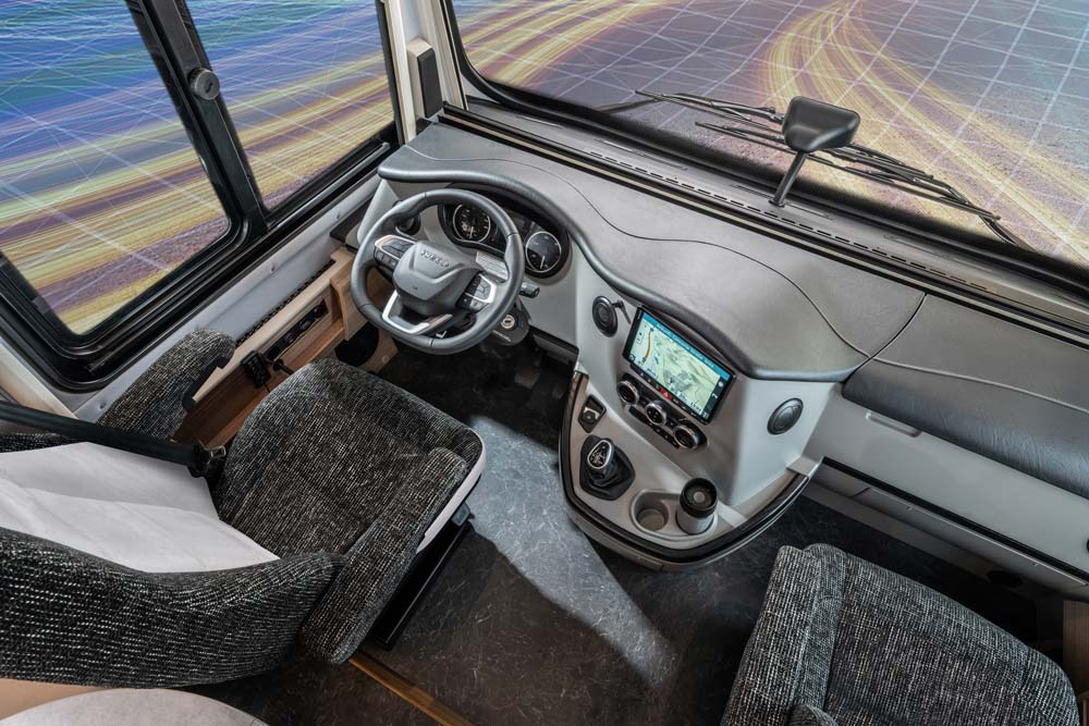Das Foto zeigt das moderne Cockpit eines Wohnmobils mit grauen Sitzen und Navi Display