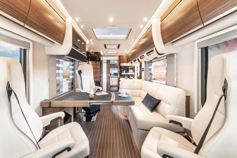 Modern luxuriöser Wohnmobil Innenraum mit weißbeigen Ledersitzen und Holzelementen
