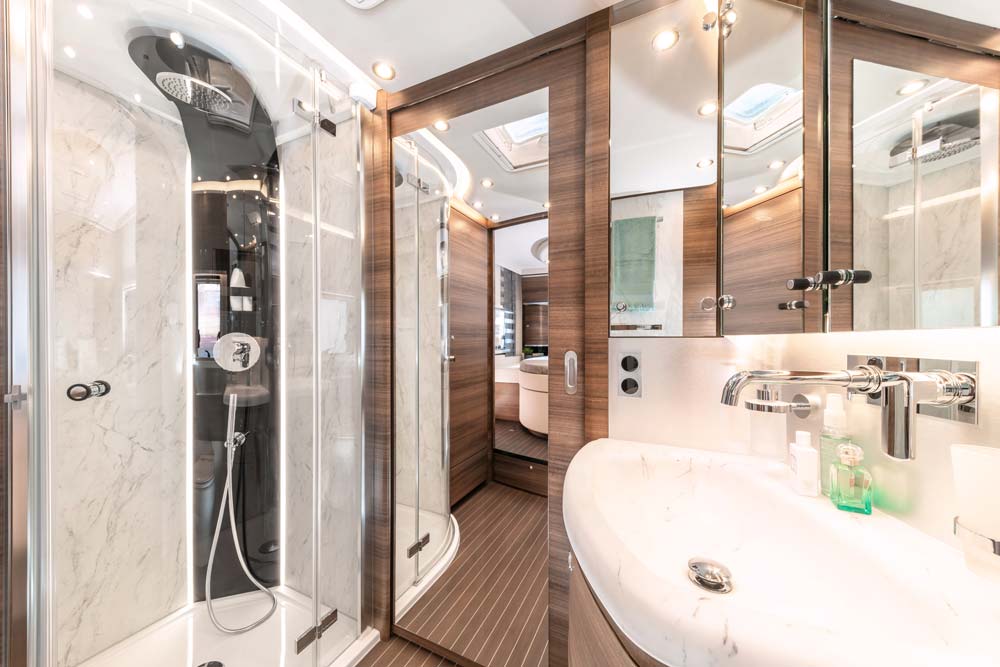 Modernes Badezimmer mit Holzelementen, Glasdusche und hellen Armaturen in Weiß