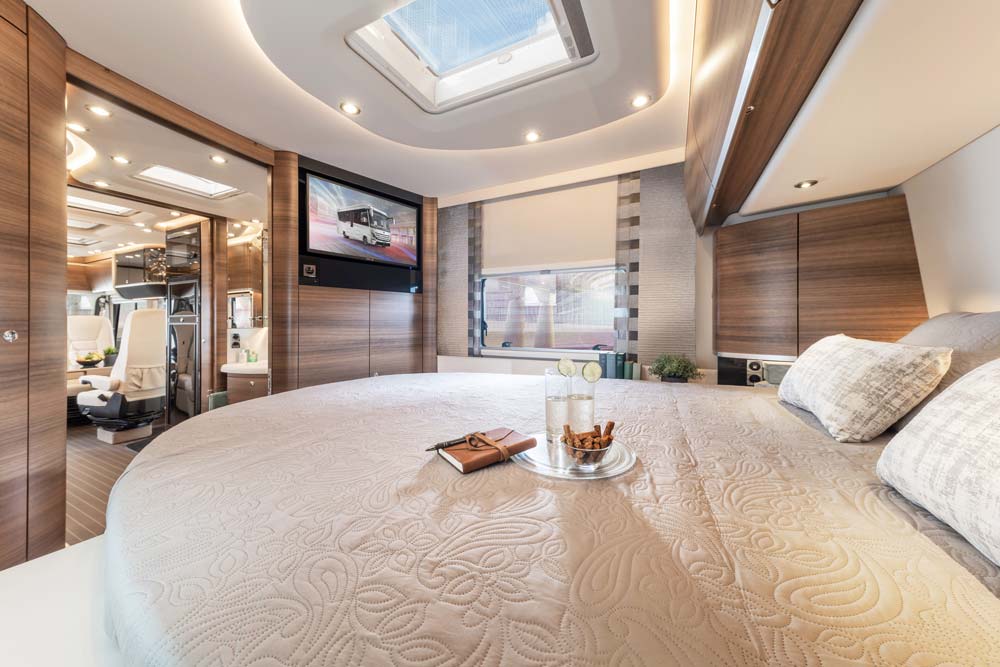 Modernes Schlafzimmer in einem Wohnmobil mit rundem Bett und hellbrauner Einrichtung