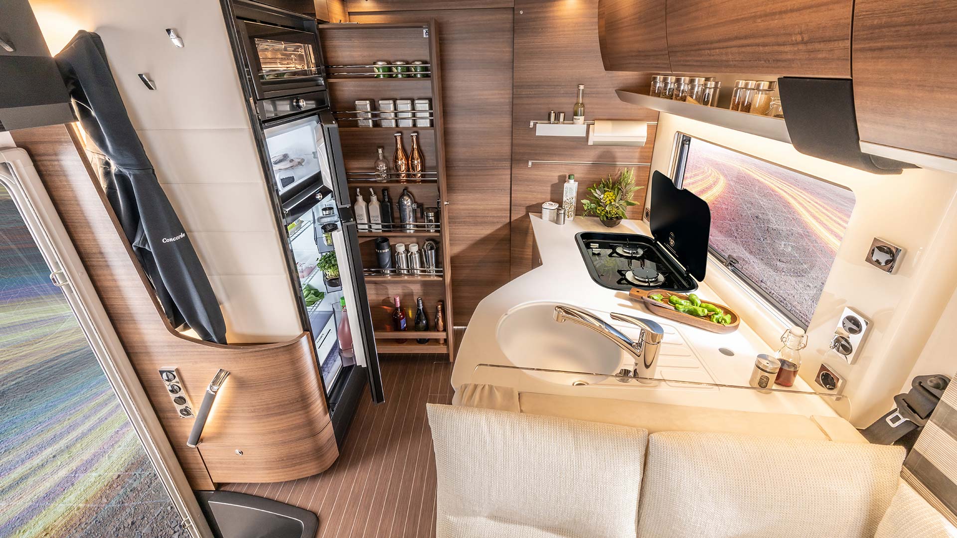 Modern Wohnmobilküche mit Holzoptik, viel Stauraum, hellen Oberflächen und Gemüse