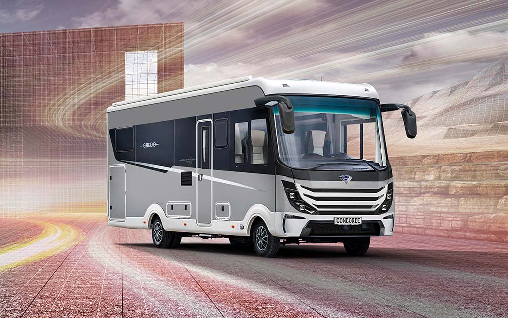 Ein moderner weißgrauer Wohnwagen mit sportlichem Design fährt auf einer städtischen Straße