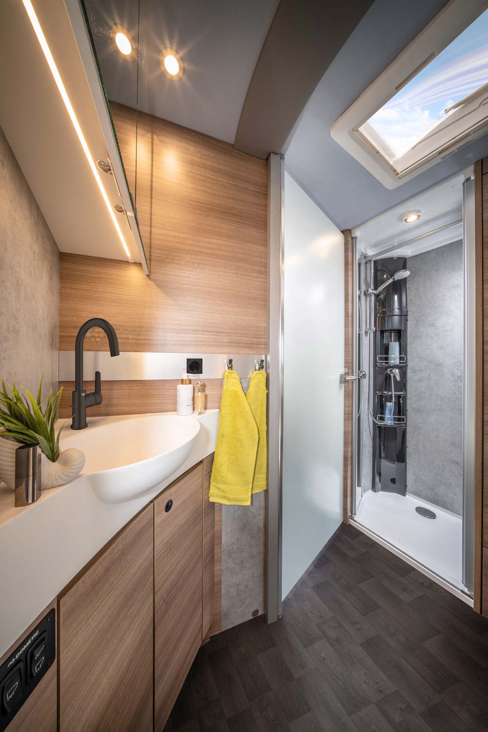 Modern Badezimmer mit Holzdekor, gelben Handtüchern und heller Duschkabine