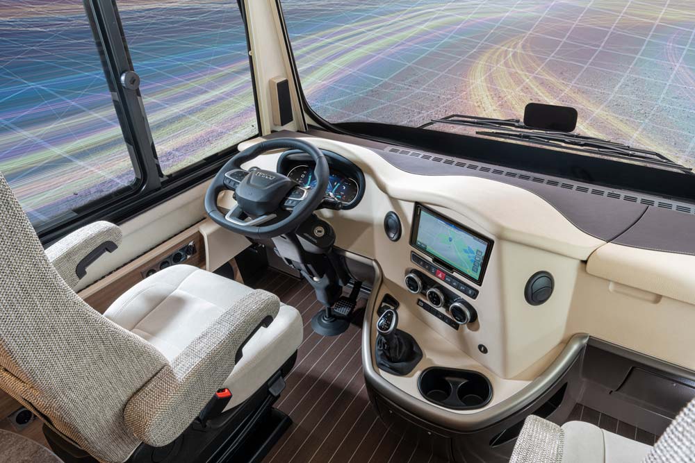 Modernes Wohnmobilcockpit mit beigen Sitzen, großem Lenkrad und Navigationsdisplay