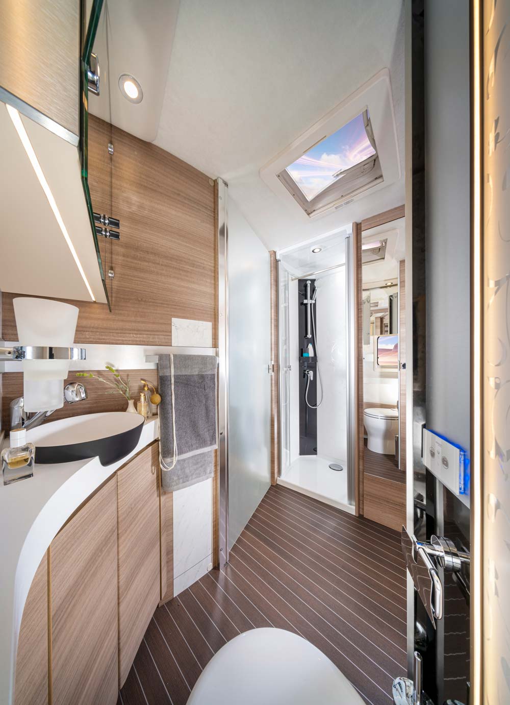 Modern Wohnmobil Badezimmer mit Holzelementen sowie großer Dusche und Dachfenster