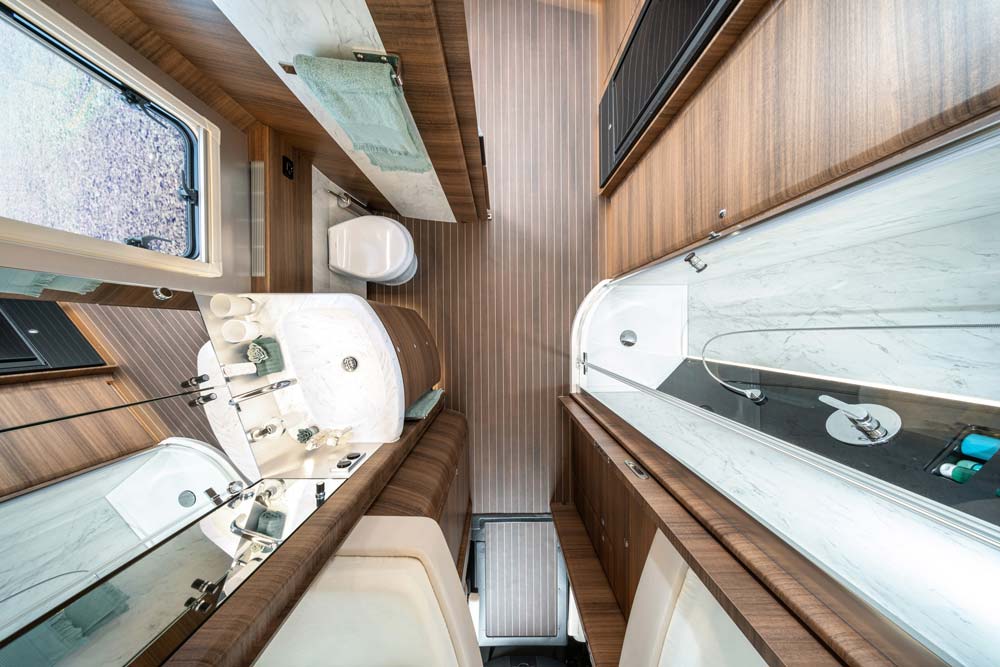 Modern Wohnmobil-Badezimmer mit Holzdekor, Glasdusche und weißem Waschbecken