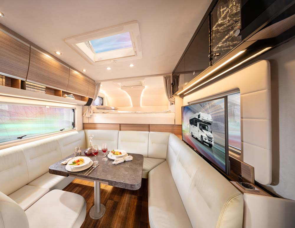 Geräumiges Wohnmobil mit heller Ledersitzbank, gedecktem Tisch und großem Dachfenster
