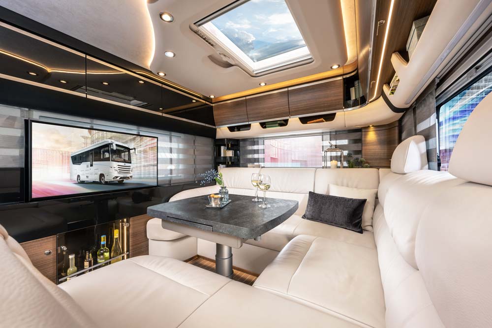 Luxuriöses Wohnmobilinterieur mit cremefarbenen Sitzflächen und Oberlicht im Dach