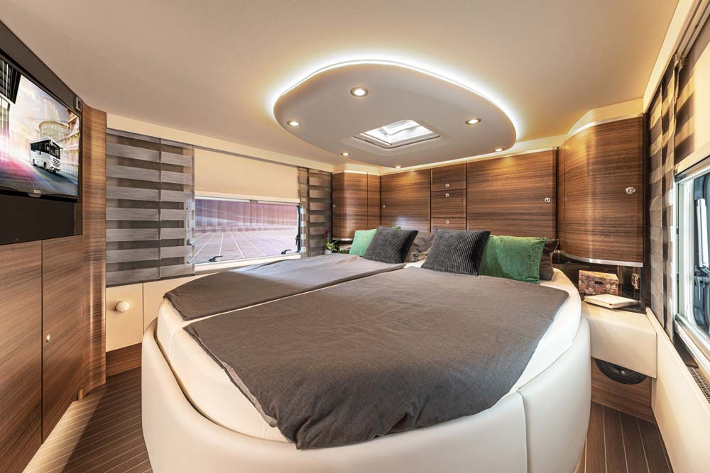 Modern Schlafzimmer in einem Wohnmobil mit großem Bett, Holzdekor und LED Beleuchtung