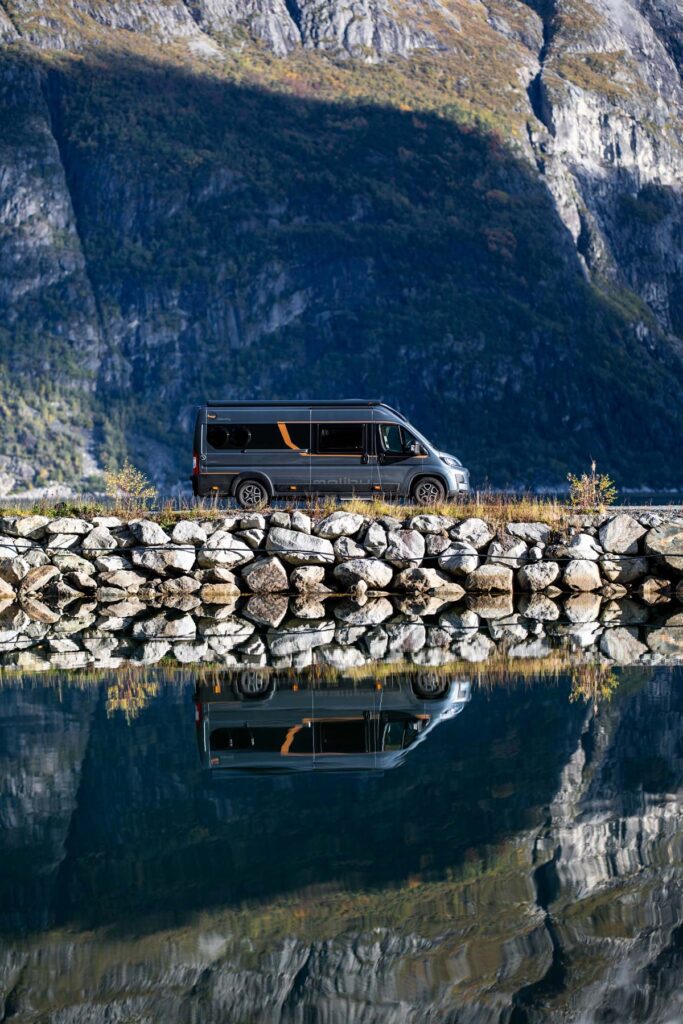 Ein schwarzer Van mit orangenen Akzenten steht vor einer steinigen Berglandschaft