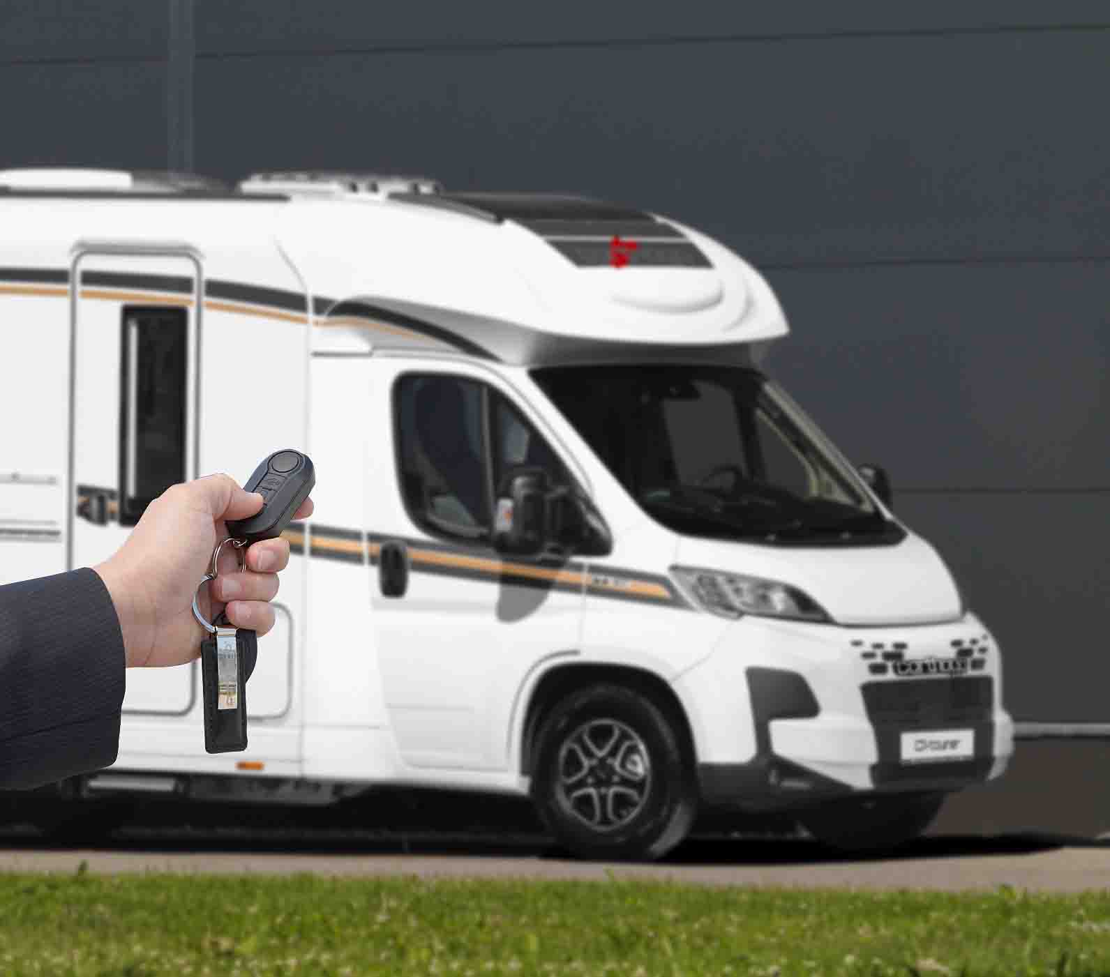 Eine Hand mit Autoschlüssel hält eine Fernbedienung vor einem weißen Wohnmobil