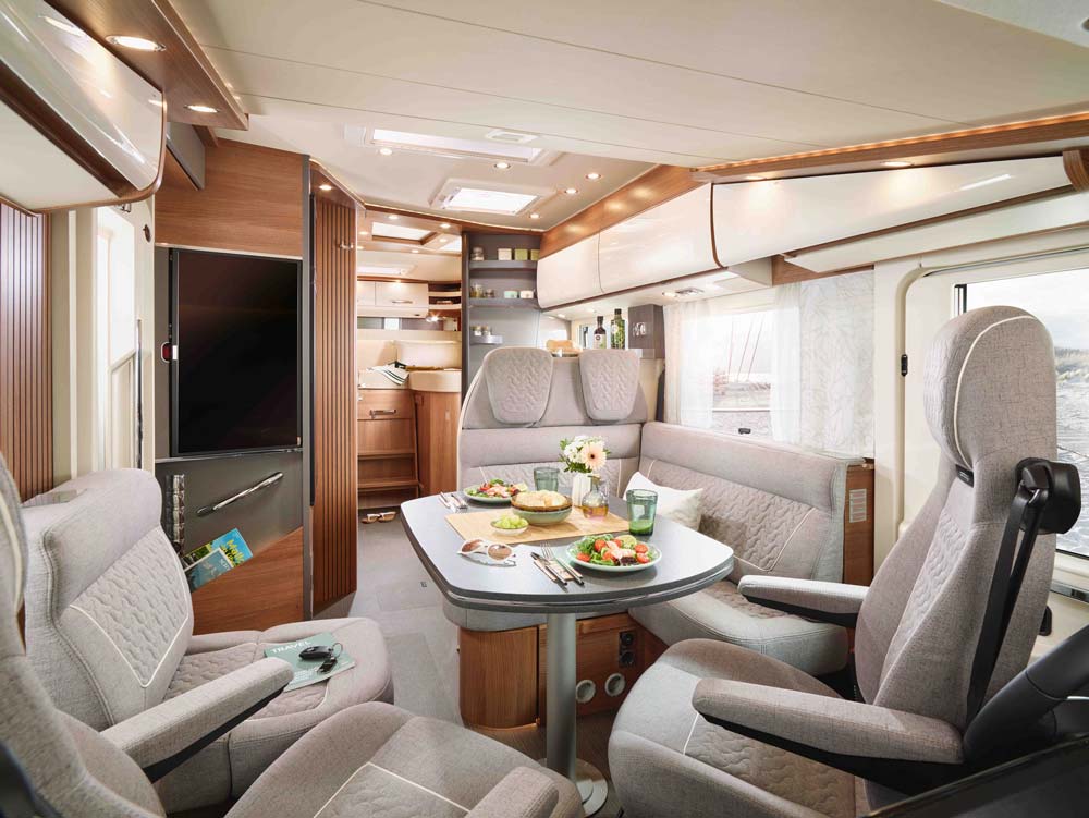 Modernes Wohnmobil mit bequemen grauen Sitzen und gedecktem Esstisch im hellen Interieur
