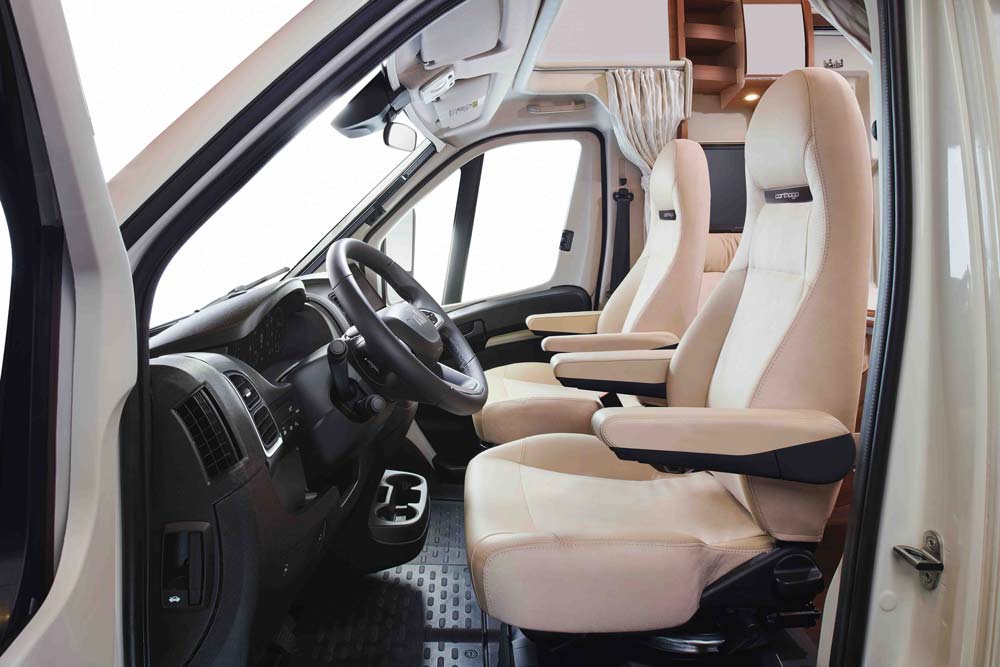 Zwei bequeme helle Vordersitze in einem modernen Wohnmobil mit Armlehnen und Sicht auf das Cockpit