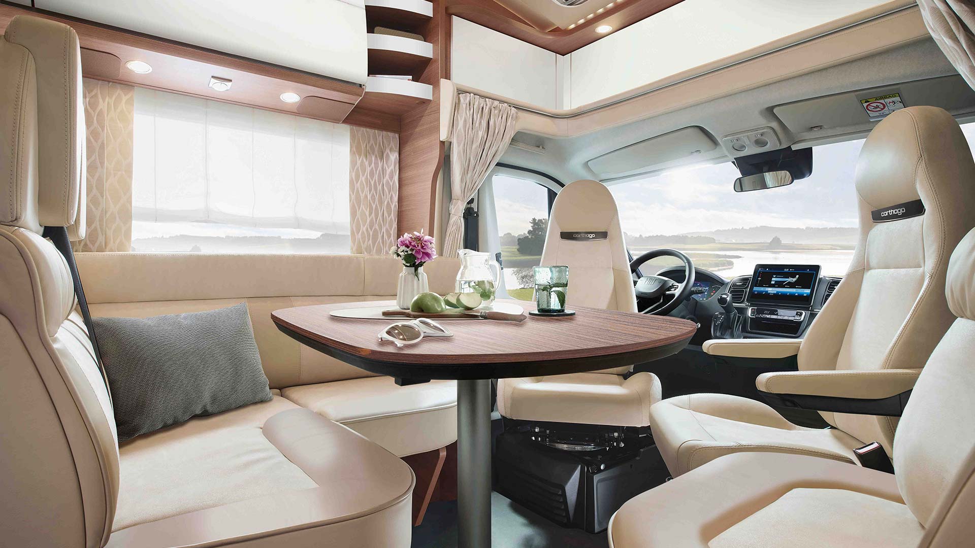 Eleganter Wohnbereich im Wohnmobil mit hellem Leder, gedecktem Tisch und Panoramaausblick