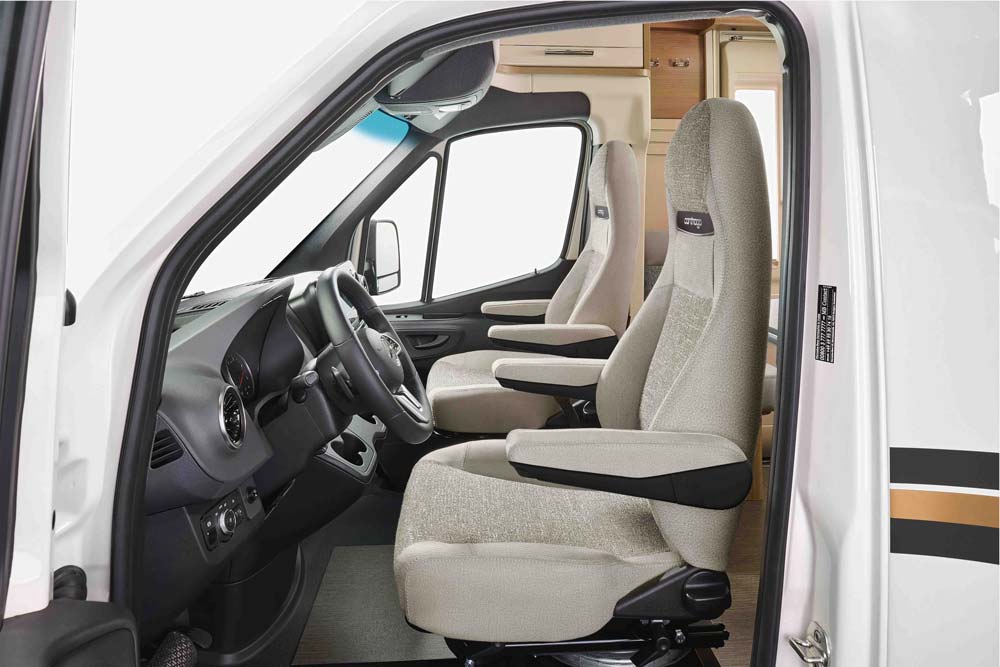 Zwei helle gepolsterte Vordersitze in einem modernen Wohnmobil mit Holzdetails