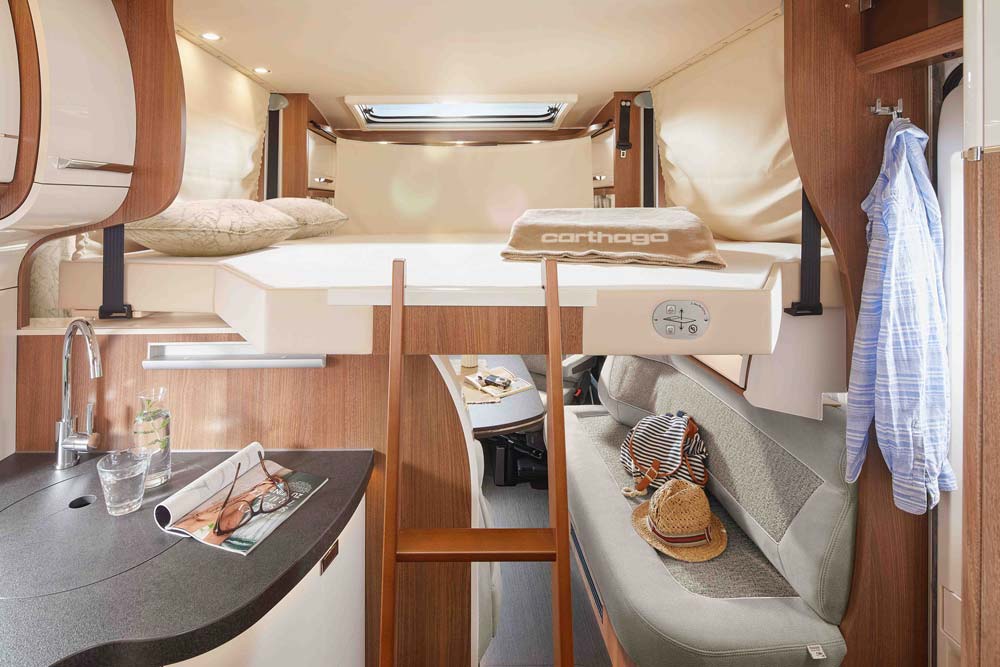 Innenansicht eines modernen Wohnmobils mit gemütlichem Hochbett und stilvoller Holzausstattung