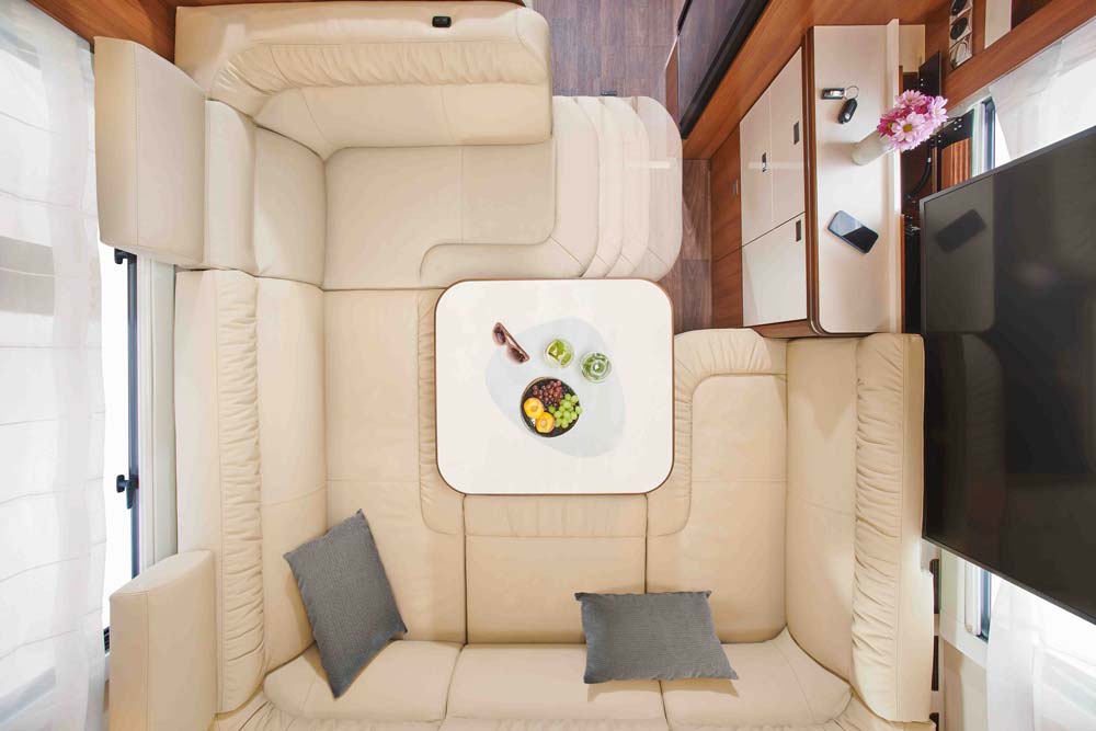 Gemütliche Wohnwagenecke mit beigem Sofa, hellem Tisch und dekorativen Kissen