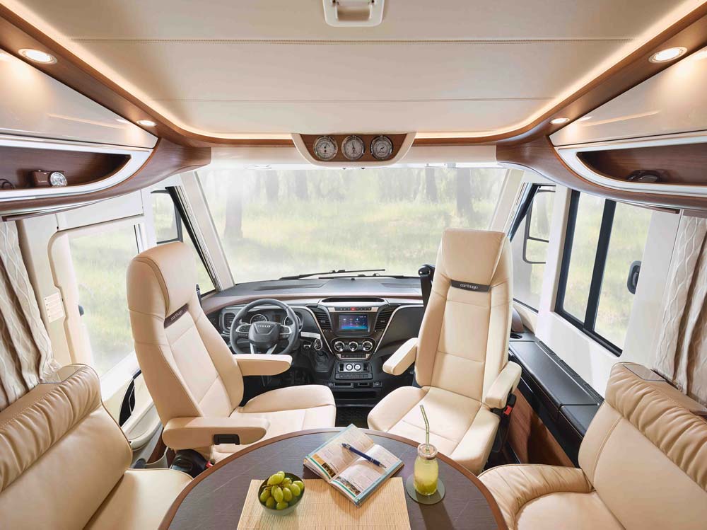 Das Bild zeigt den hellen Innenraum eines luxuriösen Wohnmobils mit Ledersitzen