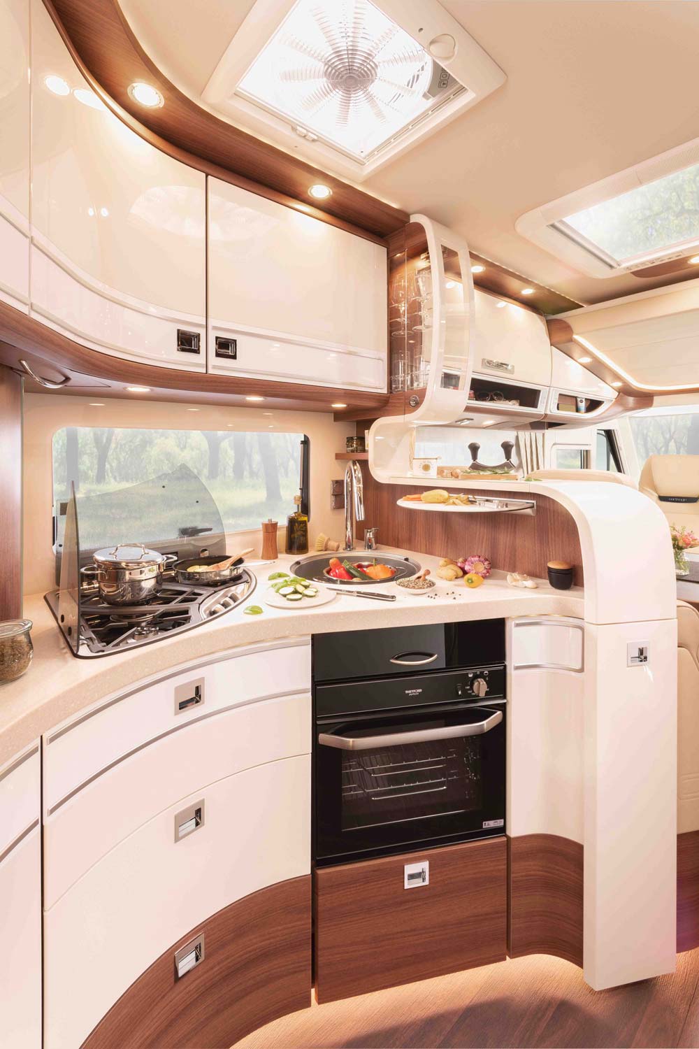 Elegante Wohnmobilküche in Beige und Braun mit Herd, Ofen und hellem Tageslicht