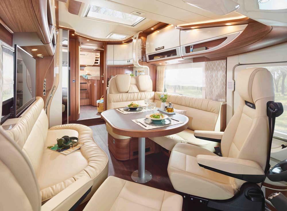 Ein luxuriöses Wohnmobil mit hellen Ledersitzen und gedecktem Tisch im modernen Design